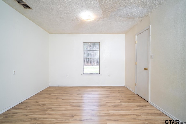 spare room with a textured ceiling and light hardwood / wood-style flooring