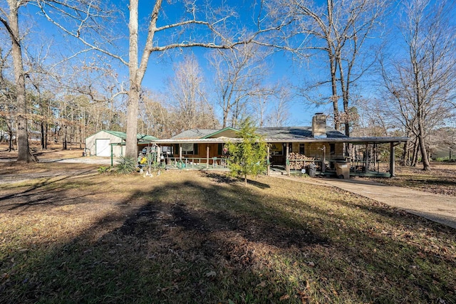 view of front of home featuring a porch, a garage, a front yard, and an outdoor structure