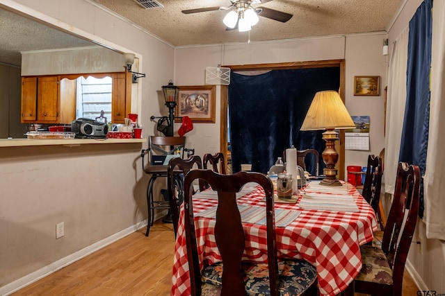 dining space featuring light hardwood / wood-style floors, a textured ceiling, ceiling fan, and ornamental molding