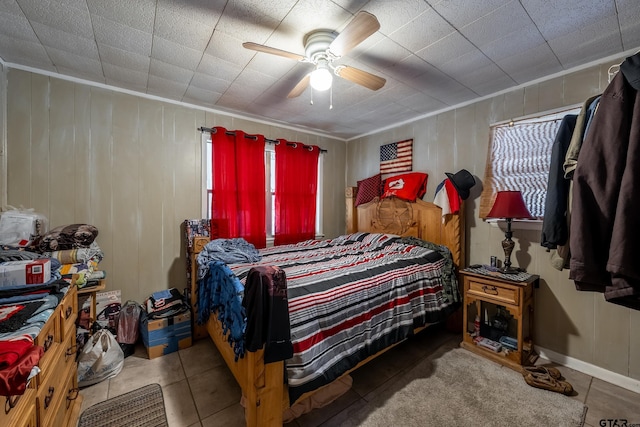 tiled bedroom featuring ceiling fan and wood walls