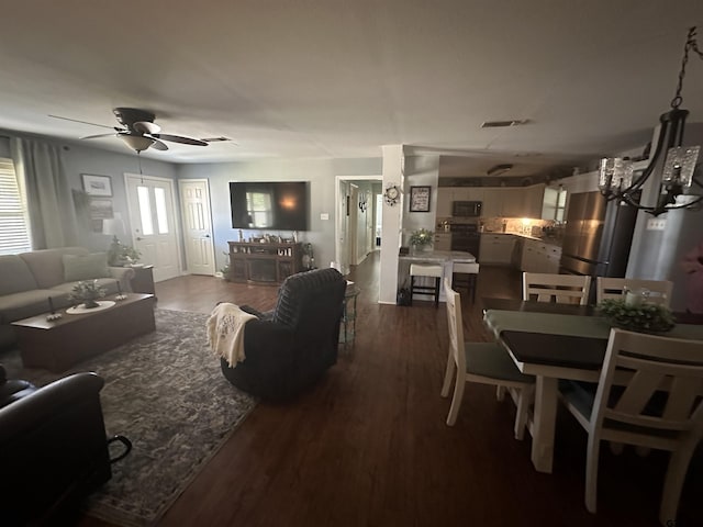 living room with ceiling fan with notable chandelier, dark wood finished floors, and visible vents