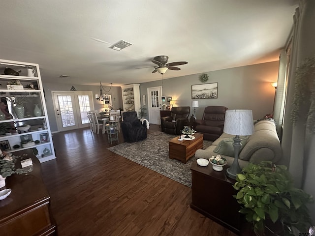 living room featuring ceiling fan, visible vents, and dark wood finished floors