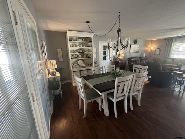 dining space featuring dark wood-type flooring and a notable chandelier