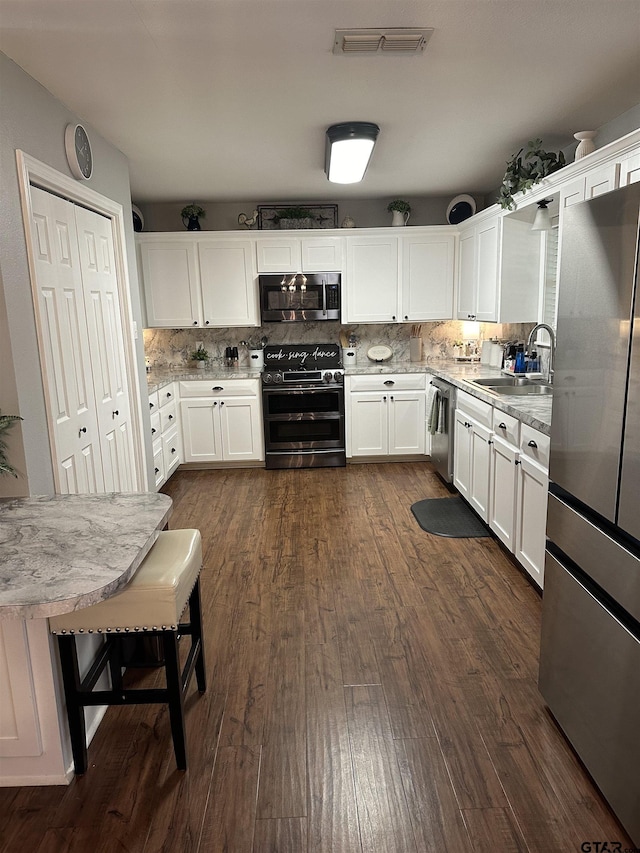 kitchen featuring stainless steel appliances, decorative backsplash, a sink, and white cabinets