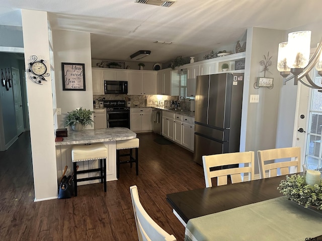 kitchen with a breakfast bar, dark wood finished floors, appliances with stainless steel finishes, white cabinets, and a sink