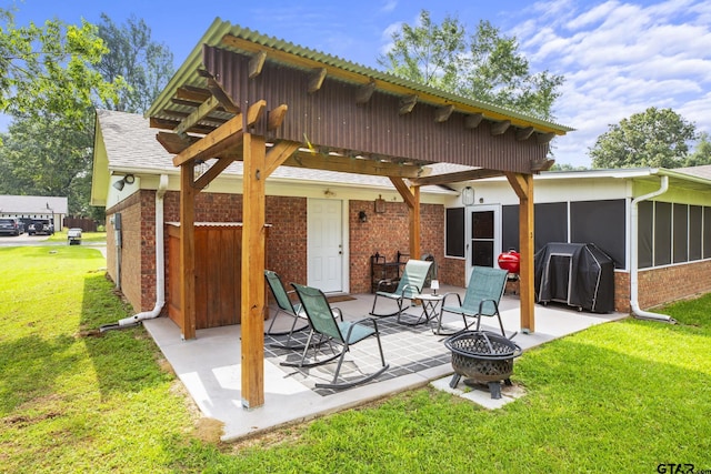 5513 Bostick Dr, Tyler, TX 75707 - rear view of house with brick siding, a patio, a sunroom, a yard, and a fire pit
