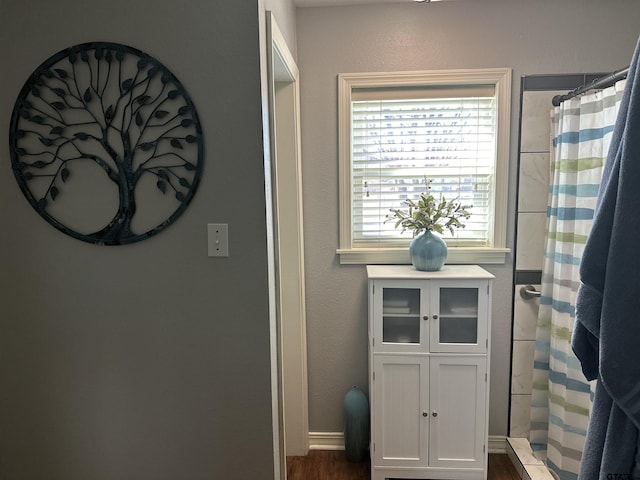 bathroom with a stall shower, wood finished floors, and a textured wall