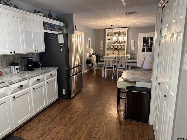 kitchen featuring hanging light fixtures, visible vents, white cabinets, and freestanding refrigerator