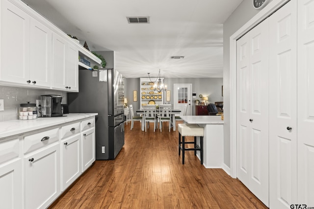 5513 Bostick Dr, Tyler, TX 75707 - kitchen featuring a chandelier, white cabinetry, dark wood-style floors, tasteful backsplash, and freestanding refrigerator