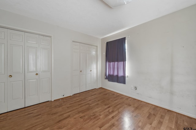 110 N Green St, Hawkins, TX 75765 - unfurnished bedroom featuring light wood-style floors, baseboards, and two closets