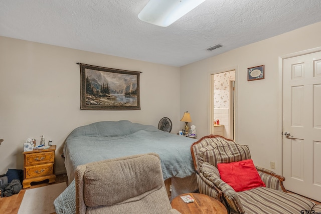 110 N Green St, Hawkins, TX 75765 - bedroom with connected bathroom, wood finished floors, visible vents, and a textured ceiling