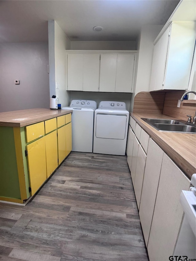 laundry area featuring cabinets, separate washer and dryer, sink, and hardwood / wood-style floors