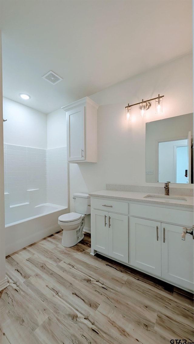 full bathroom featuring shower / bathing tub combination, wood-type flooring, vanity, and toilet