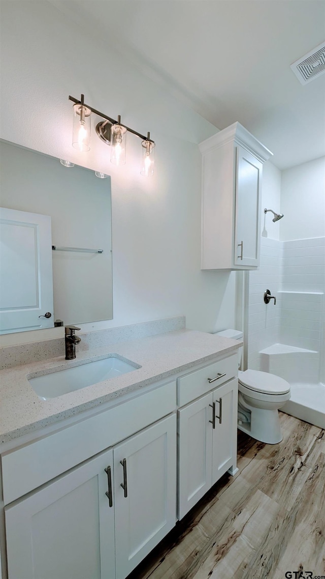 bathroom featuring a shower, hardwood / wood-style floors, vanity, and toilet