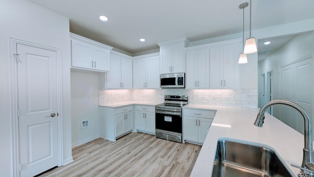 kitchen with sink, white cabinetry, stainless steel appliances, and hanging light fixtures