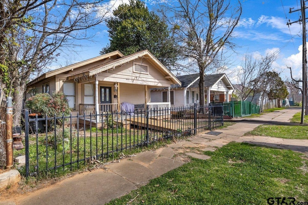 bungalow with covered porch and a fenced front yard