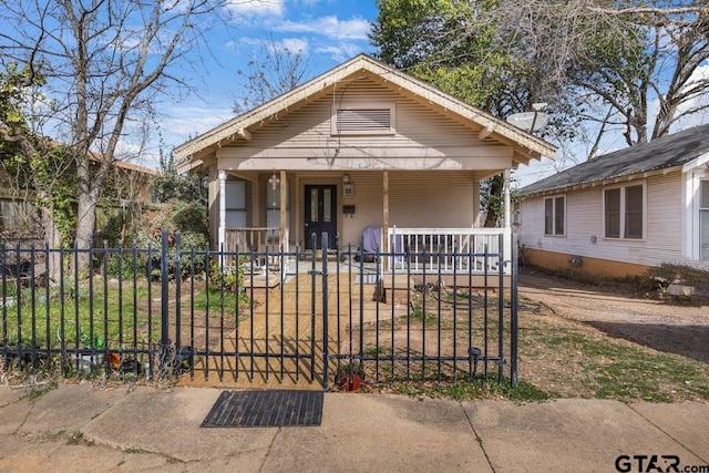 bungalow-style house featuring covered porch, a fenced front yard, and a gate