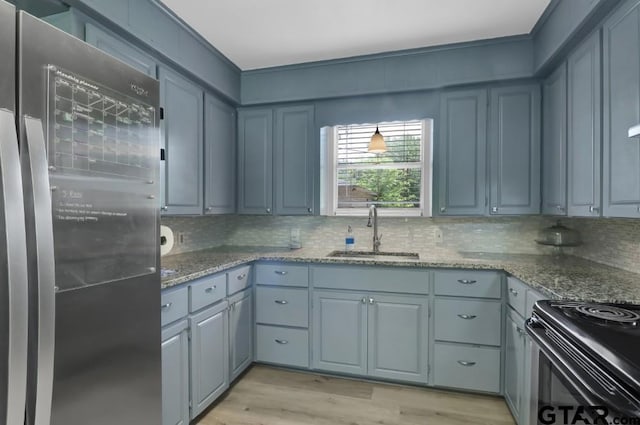 150 Gambrell St, Rusk, TX 75785 - kitchen with freestanding refrigerator, backsplash, light wood-style flooring, stone counters, and black range with electric cooktop