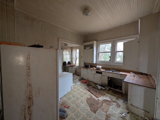 kitchen featuring wooden ceiling, a sink, and freestanding refrigerator