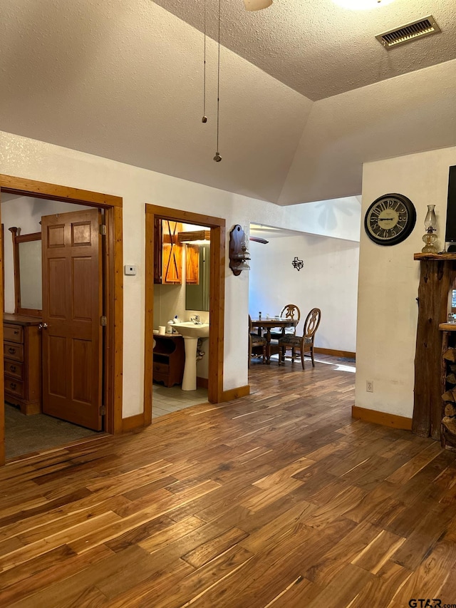 living room with a textured ceiling, hardwood / wood-style flooring, and vaulted ceiling