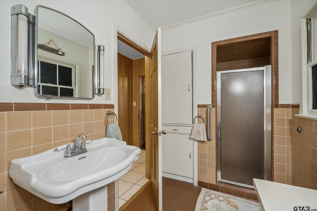 full bathroom featuring tile walls, tile patterned floors, a stall shower, and a sink