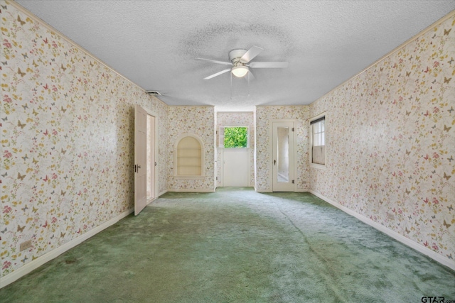 carpeted empty room with baseboards, a ceiling fan, a textured ceiling, and wallpapered walls