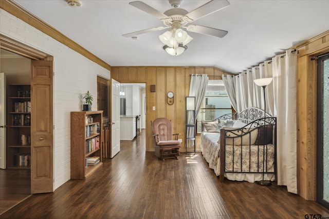 living area with vaulted ceiling, a ceiling fan, crown molding, wooden walls, and dark wood-style flooring