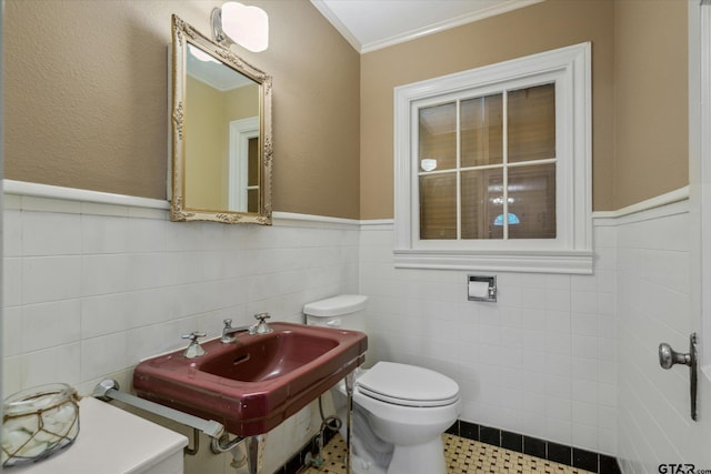 bathroom with crown molding, tile walls, toilet, and wainscoting