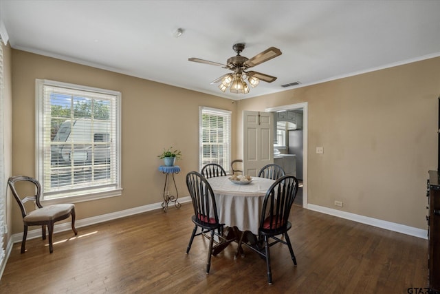 dining area featuring visible vents, dark wood-type flooring, crown molding, baseboards, and ceiling fan