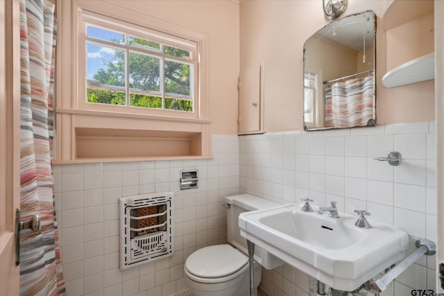 bathroom featuring tile walls, heating unit, a sink, and toilet
