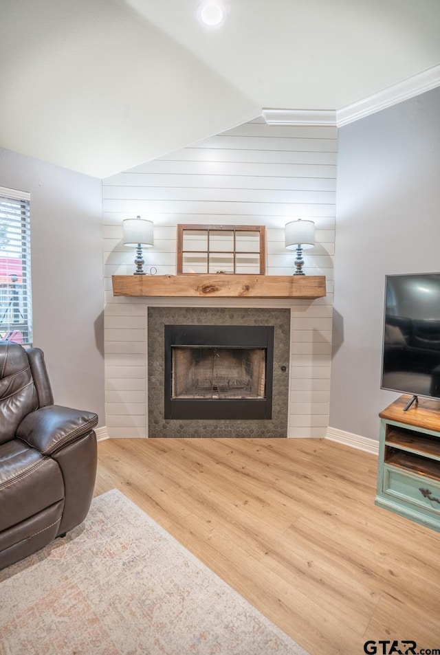 living room featuring lofted ceiling, a tiled fireplace, and hardwood / wood-style floors