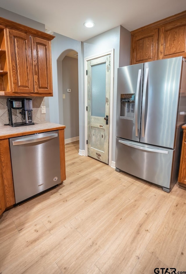 kitchen featuring backsplash, light hardwood / wood-style flooring, and appliances with stainless steel finishes