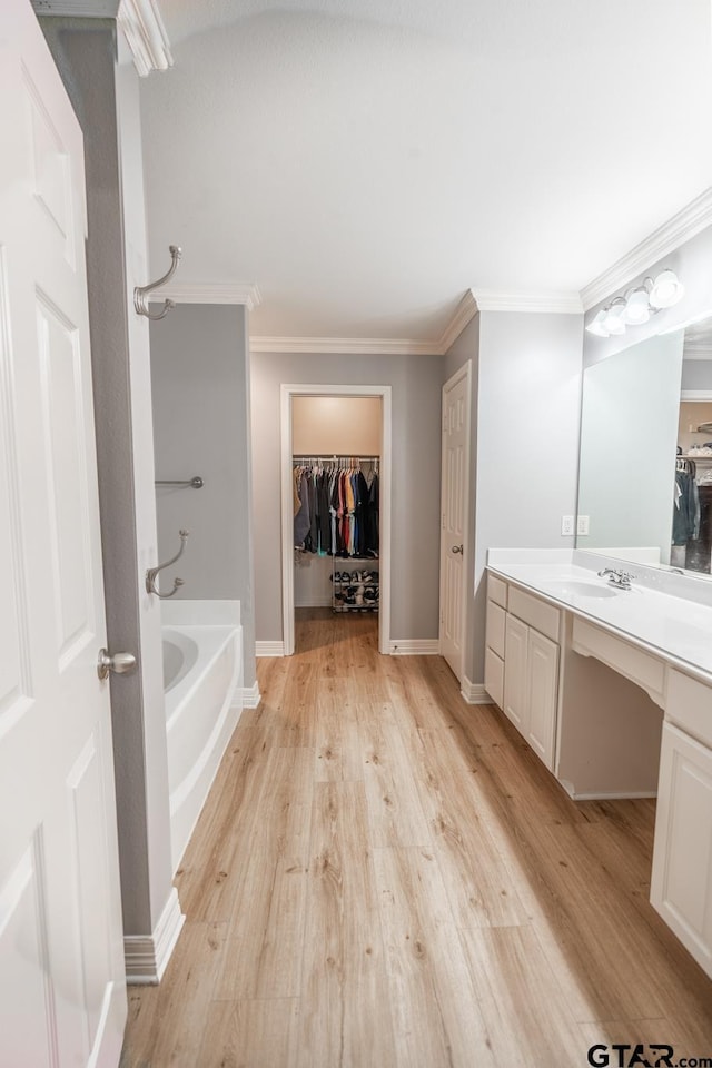 bathroom with crown molding, vanity, a tub, and hardwood / wood-style flooring