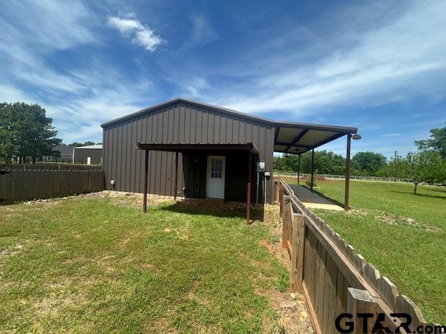 view of pole building featuring fence and a yard