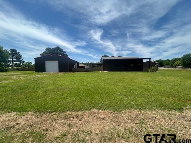 view of yard with a garage, a pole building, and an outbuilding