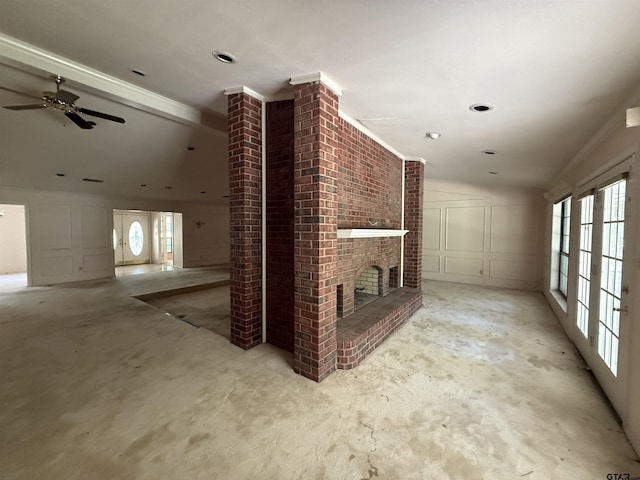 unfurnished living room featuring lofted ceiling, a brick fireplace, concrete flooring, ceiling fan, and a decorative wall