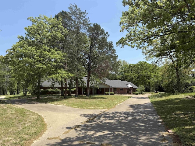 view of property's community featuring concrete driveway and a lawn