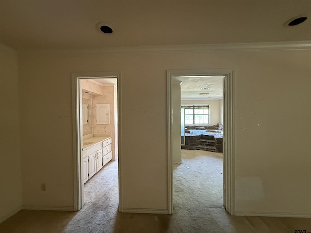 corridor featuring light colored carpet, baseboards, and crown molding