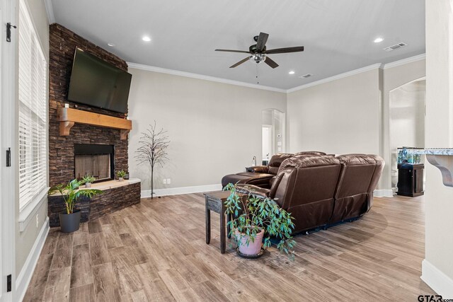 living room featuring visible vents, ornamental molding, wood finished floors, arched walkways, and a fireplace