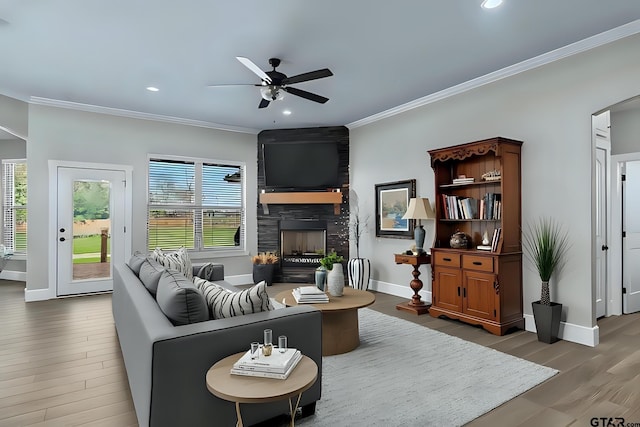 living room featuring a large fireplace, plenty of natural light, wood finished floors, and ornamental molding