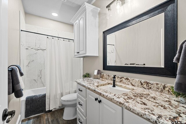 full bath featuring vanity, toilet, wood finished floors, and shower / bath combo with shower curtain