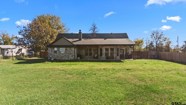 rear view of house with a fenced backyard, a chimney, a yard, and brick siding