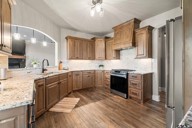 kitchen with dark wood-style floors, stainless steel appliances, light stone counters, and a sink