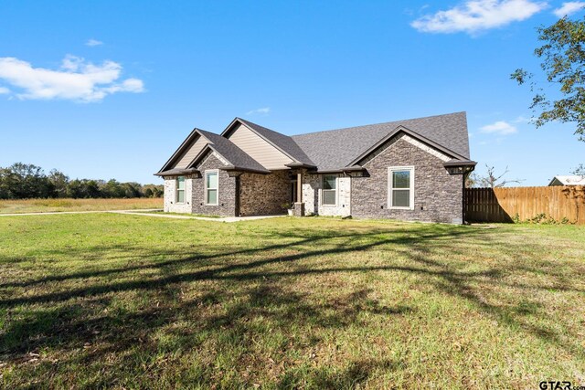 view of front of property featuring a front yard, fence, and a shingled roof