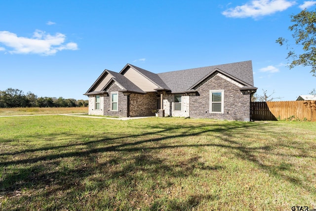 view of front of property featuring a shingled roof, a front lawn, and fence