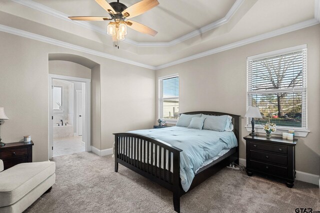 bedroom with a raised ceiling, carpet flooring, crown molding, and arched walkways