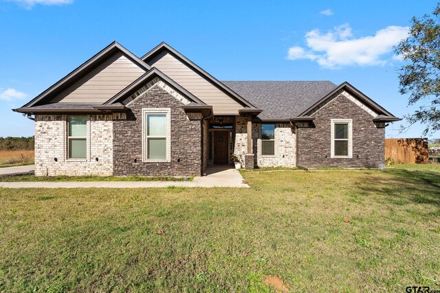 view of front of property featuring brick siding, a front lawn, and fence