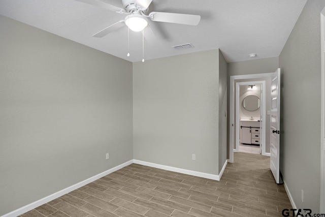 unfurnished bedroom with a sink, wood finished floors, visible vents, a ceiling fan, and baseboards