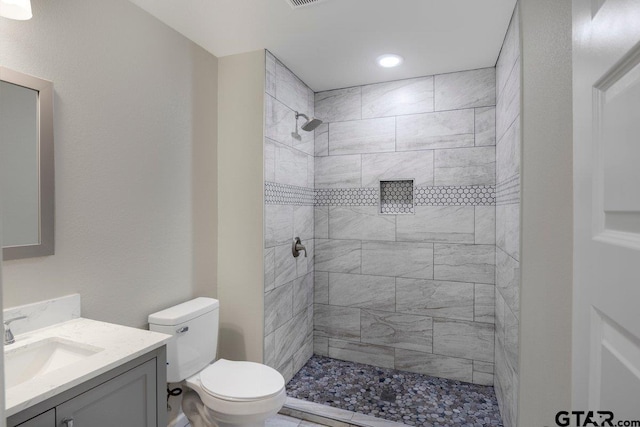 bathroom with vanity, toilet, and tiled shower