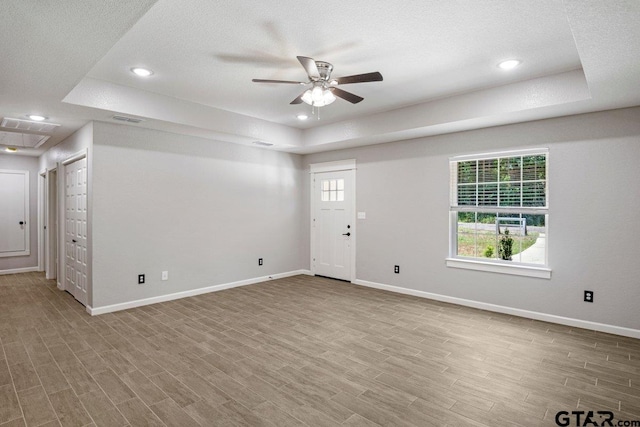 spare room featuring a ceiling fan, a tray ceiling, visible vents, and wood finished floors